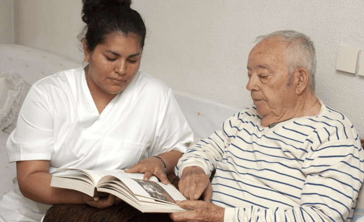 persoonlijke aandacht - verpleegkundige leest samen met oudere man een boek